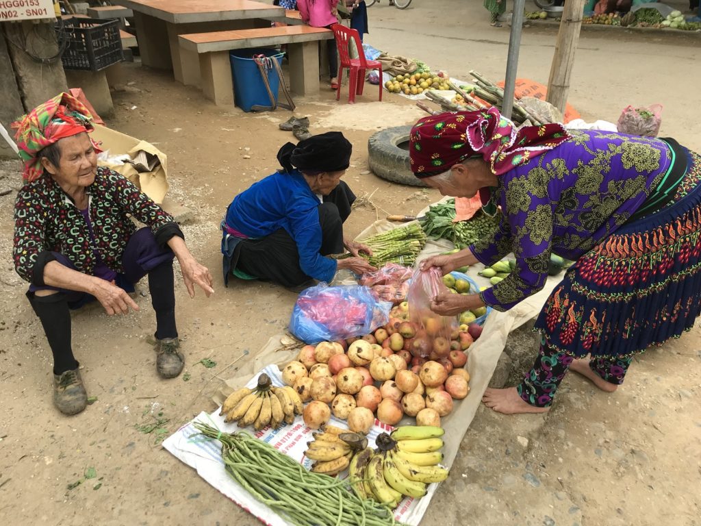 Drie Hmong vrouwen verkopen fruit op markt