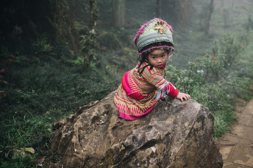Hmong kind zit op rots bij homestay Sapa